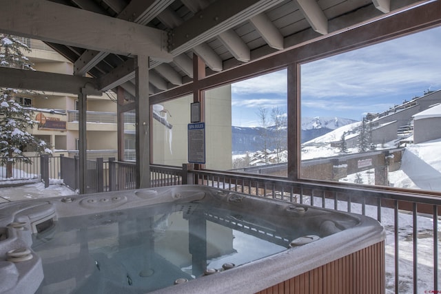 snow covered deck featuring a mountain view and a hot tub