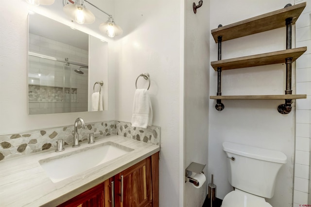 bathroom with vanity, toilet, a shower with shower door, and backsplash