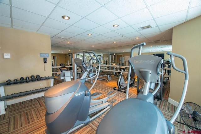 exercise room featuring a paneled ceiling and carpet floors