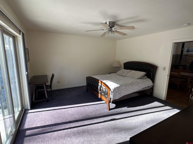 bedroom with a textured ceiling, dark carpet, and ceiling fan