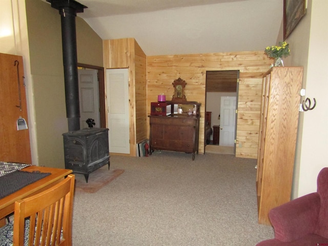 interior space featuring carpet flooring, wooden walls, and vaulted ceiling