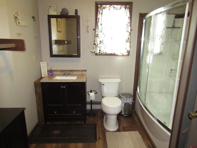 full bathroom featuring shower / bath combination with glass door, vanity, wood-type flooring, and toilet