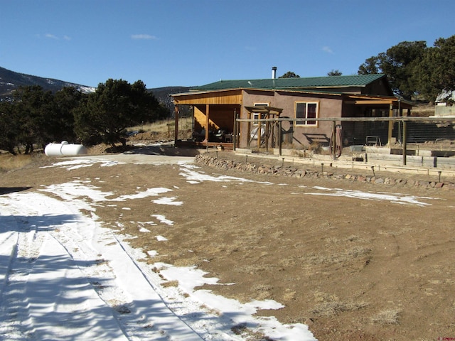 snow covered rear of property featuring a mountain view