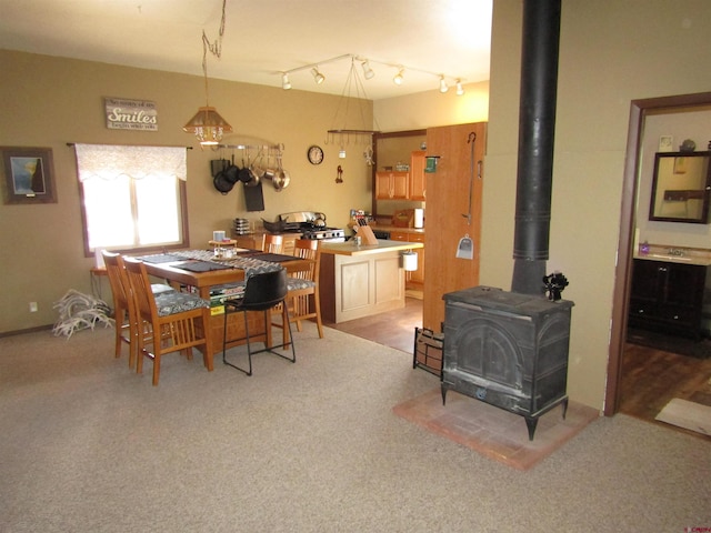 carpeted dining space with a wood stove and track lighting