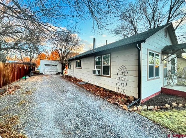 view of home's exterior with cooling unit, a garage, and an outbuilding