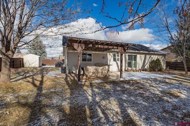 back of property with a pergola, a patio area, and a storage unit