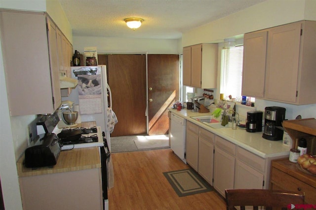 kitchen with dishwasher, light wood-type flooring, range with gas cooktop, a textured ceiling, and sink