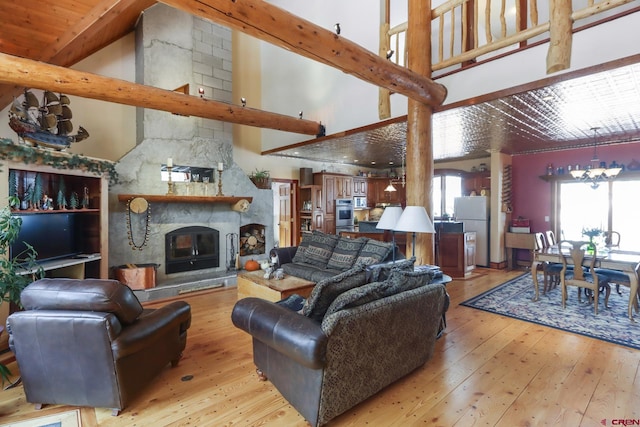 living room featuring a high ceiling, a fireplace, light wood-type flooring, and a notable chandelier