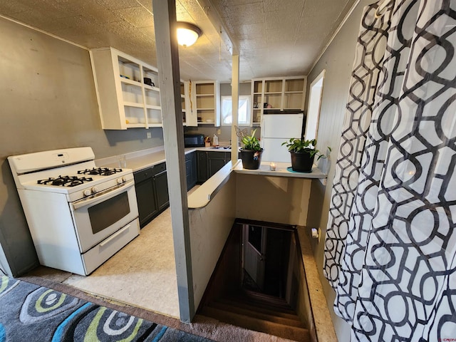 kitchen with white appliances, a textured ceiling, and white cabinetry