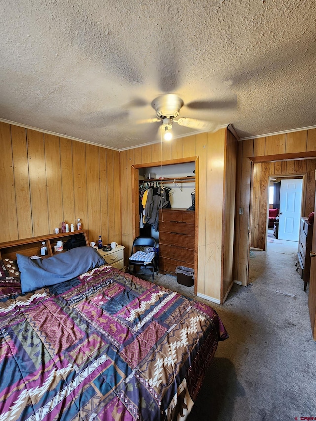 bedroom with a closet, carpet, ceiling fan, wooden walls, and a textured ceiling