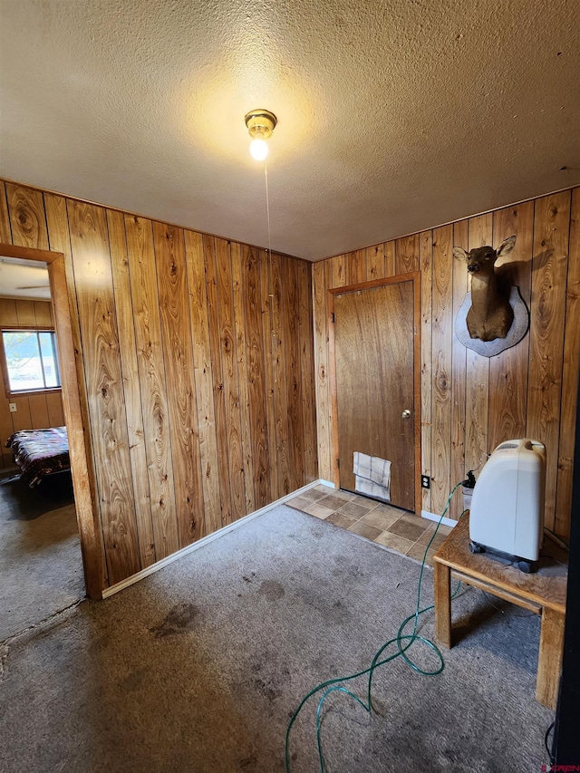 sitting room featuring carpet floors, wood walls, and a textured ceiling