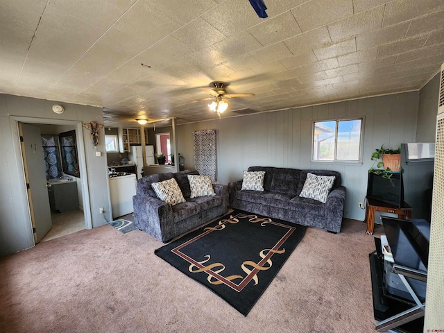 living room with wood walls, ceiling fan, and carpet