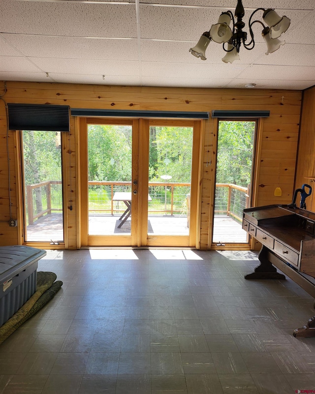 doorway to outside featuring an inviting chandelier and wood walls