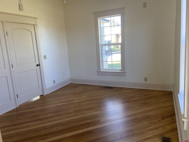 empty room featuring a wealth of natural light and dark hardwood / wood-style floors