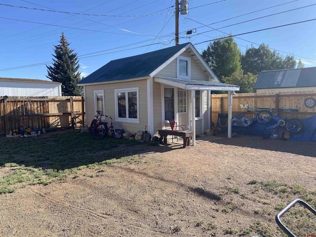 rear view of property with a lawn and an outdoor structure