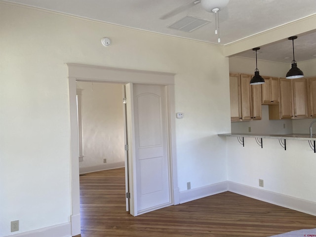 kitchen with dark wood-type flooring, light brown cabinets, and hanging light fixtures