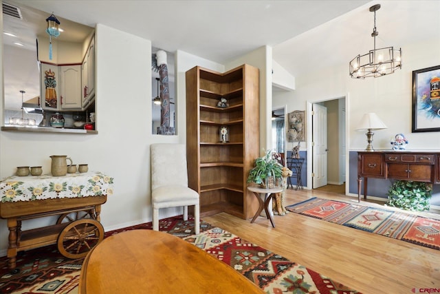 sitting room featuring light hardwood / wood-style floors, a notable chandelier, and vaulted ceiling