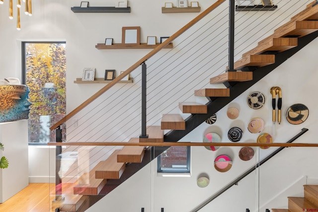 stairway with a healthy amount of sunlight and hardwood / wood-style flooring