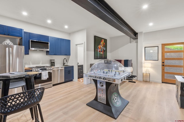 kitchen with appliances with stainless steel finishes, light hardwood / wood-style floors, blue cabinetry, and sink