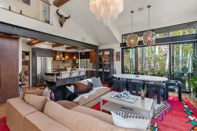 living room with a chandelier, hardwood / wood-style floors, high vaulted ceiling, beam ceiling, and sink