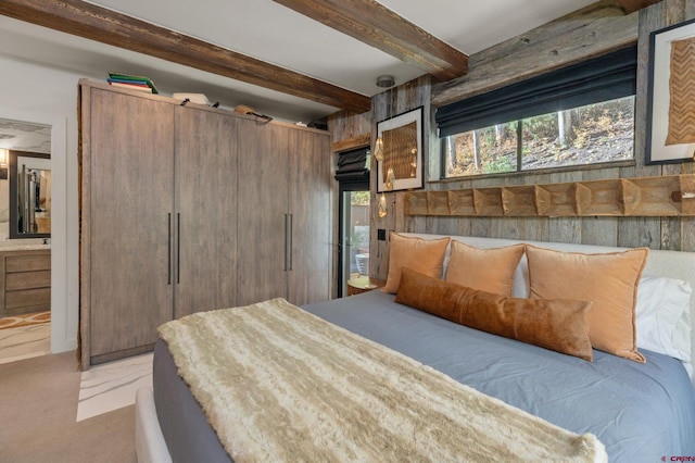 bedroom with ensuite bathroom and beamed ceiling