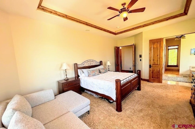 carpeted bedroom with crown molding, a tray ceiling, and ceiling fan