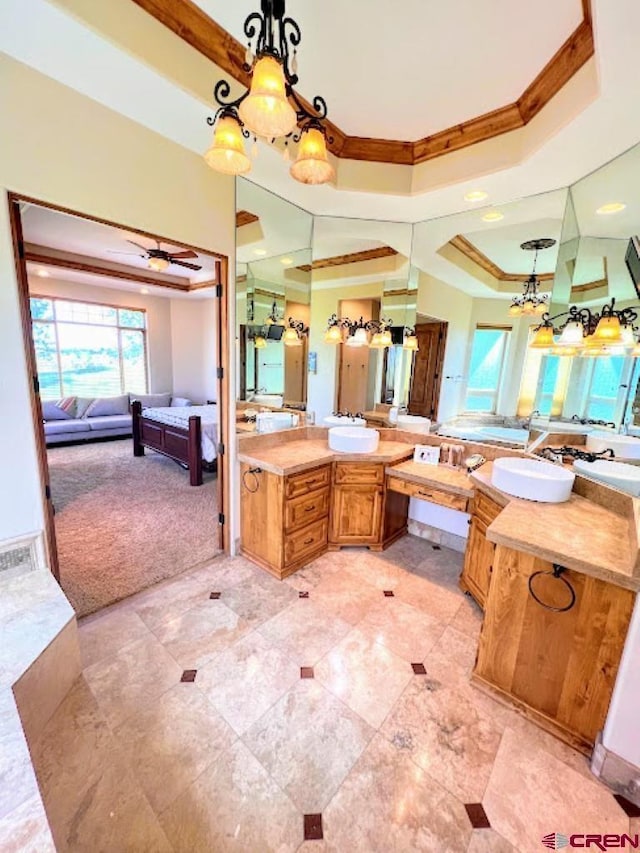 bathroom featuring a raised ceiling, ornamental molding, vanity, and ceiling fan