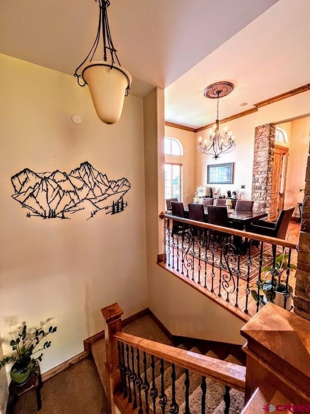 stairs featuring a notable chandelier, crown molding, and carpet flooring