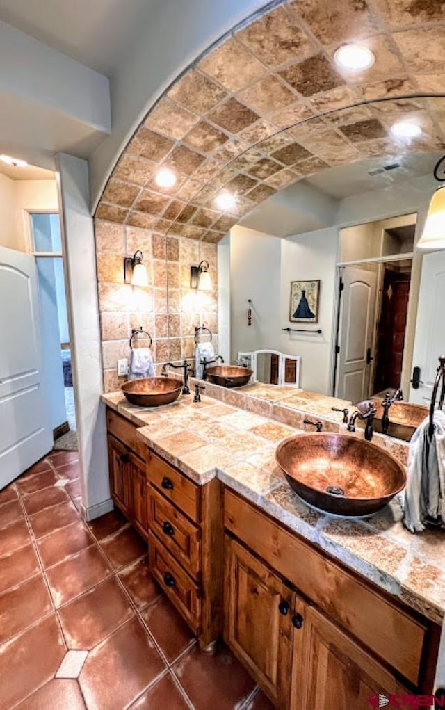 bathroom featuring brick ceiling, vanity, washer / clothes dryer, and tile patterned flooring