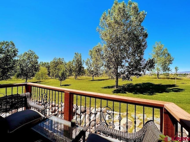 wooden terrace with a rural view and a lawn