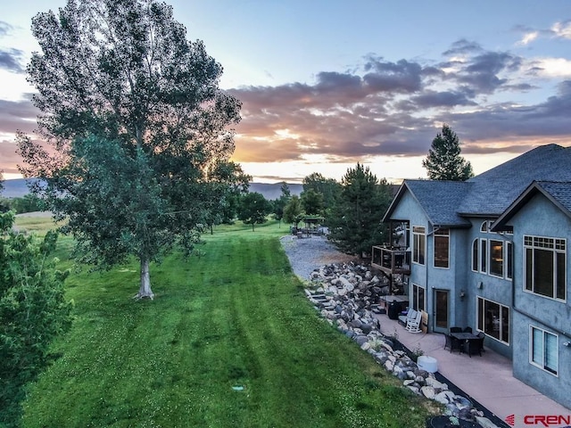 yard at dusk featuring a patio