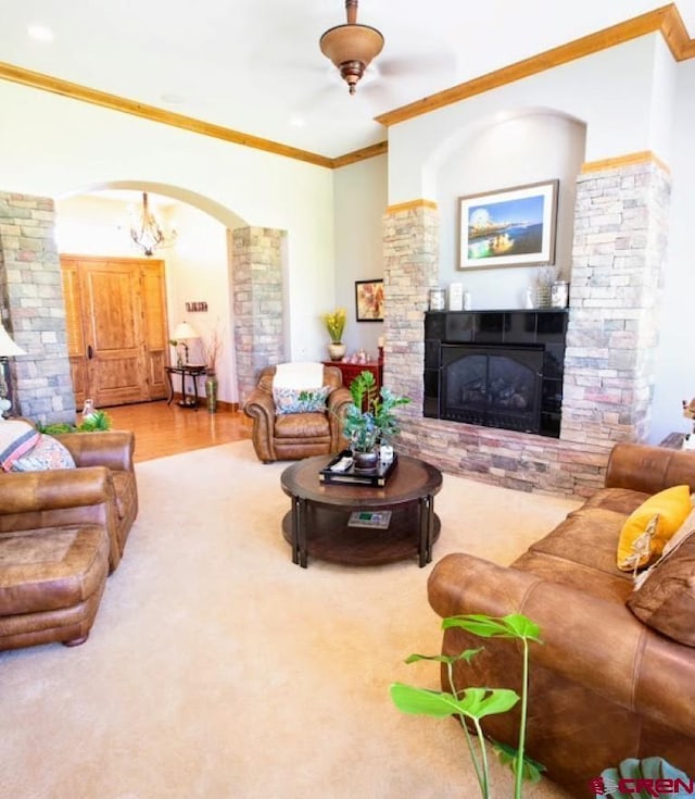 living room with ceiling fan with notable chandelier, a fireplace, and ornamental molding