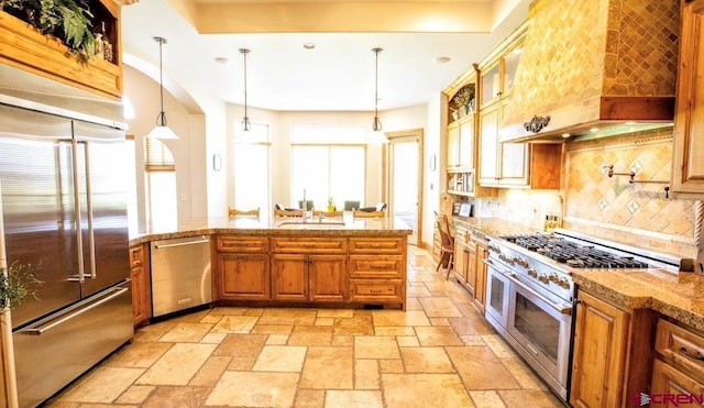 kitchen featuring high end appliances, light stone counters, decorative light fixtures, custom range hood, and decorative backsplash