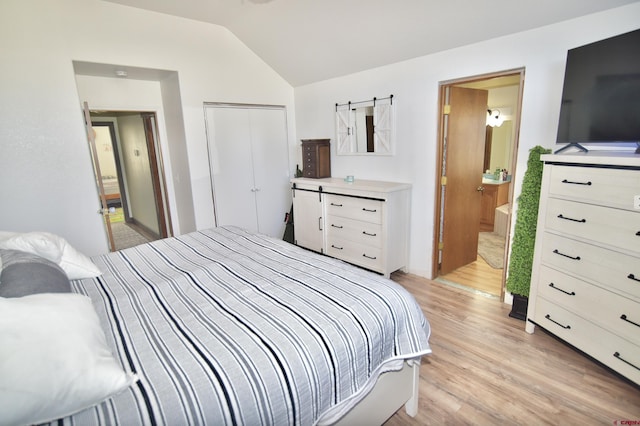 bedroom featuring light hardwood / wood-style floors, connected bathroom, and vaulted ceiling