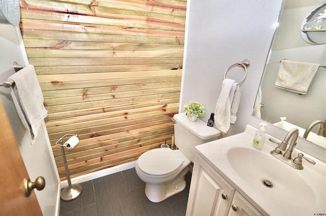 bathroom featuring wood walls, vanity, and toilet