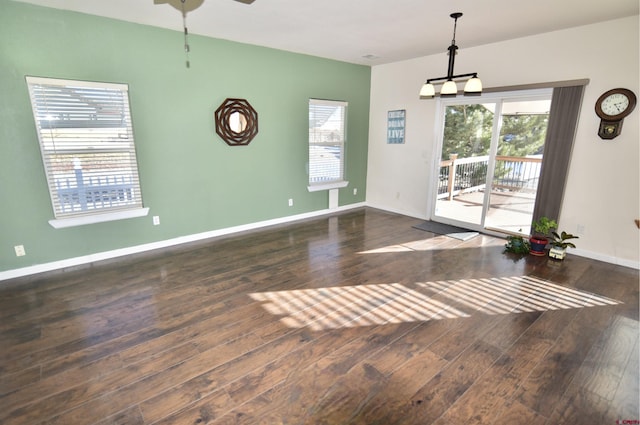 unfurnished dining area with ceiling fan with notable chandelier and dark hardwood / wood-style floors