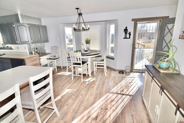 dining room with light wood-type flooring and an inviting chandelier