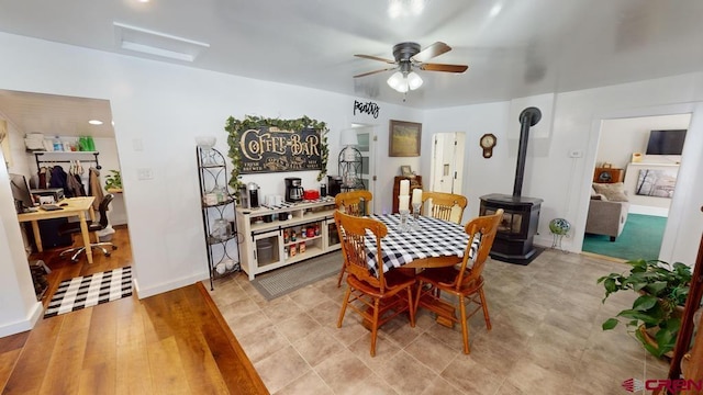 dining area featuring ceiling fan and a wood stove