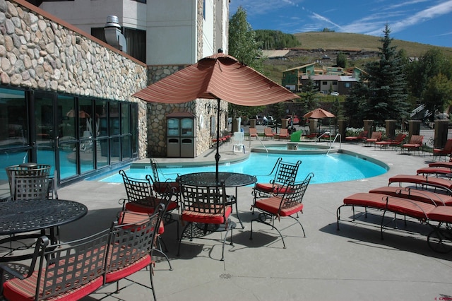 view of swimming pool featuring a hot tub, a mountain view, and a patio area