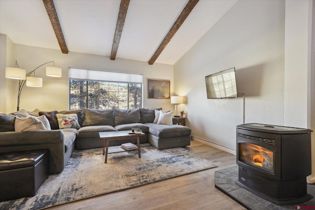 living room with a wood stove, hardwood / wood-style floors, and vaulted ceiling with beams