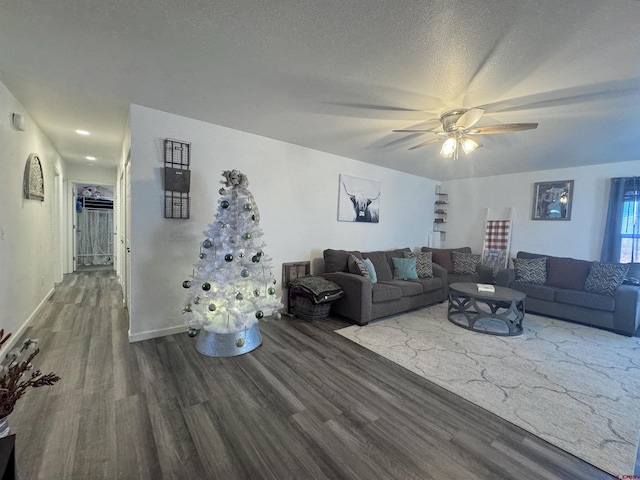 living room featuring a textured ceiling, ceiling fan, and dark wood-type flooring