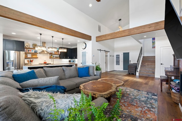 living room with high vaulted ceiling, beamed ceiling, a barn door, and dark wood-type flooring