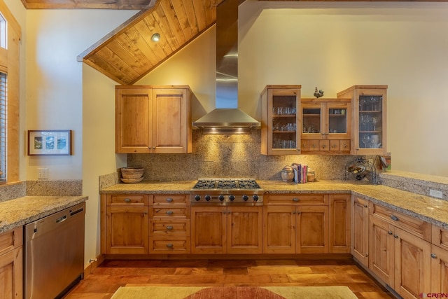 kitchen with light stone counters, appliances with stainless steel finishes, wall chimney exhaust hood, and decorative backsplash