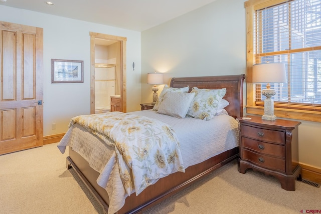 bedroom with light colored carpet and ensuite bathroom