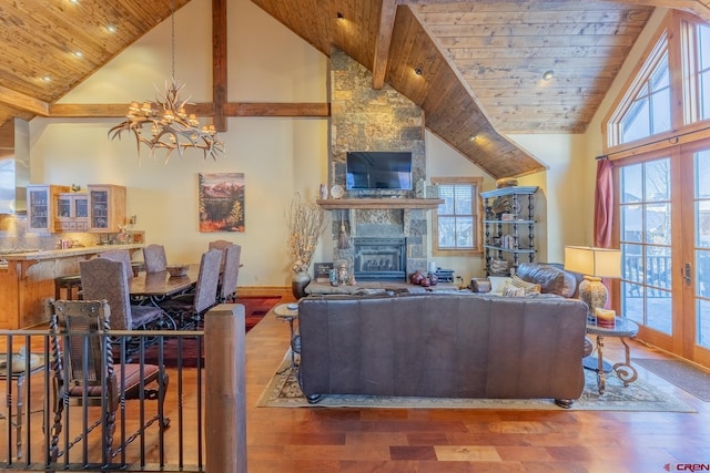 living room with a fireplace, high vaulted ceiling, a chandelier, and hardwood / wood-style floors