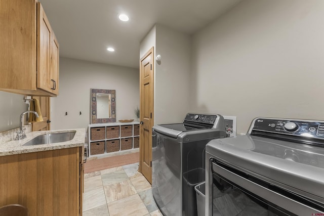 clothes washing area featuring cabinets, sink, and washing machine and clothes dryer