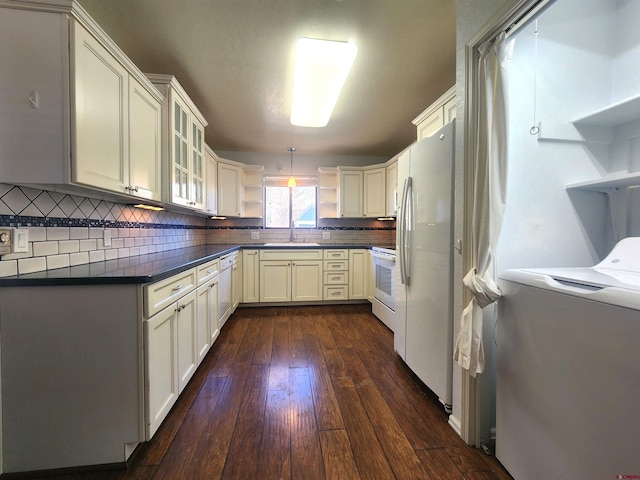 kitchen with pendant lighting, white appliances, washer / dryer, sink, and dark hardwood / wood-style floors