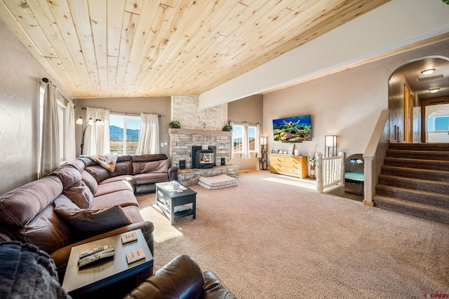 carpeted living room with wooden ceiling, lofted ceiling, and a stone fireplace