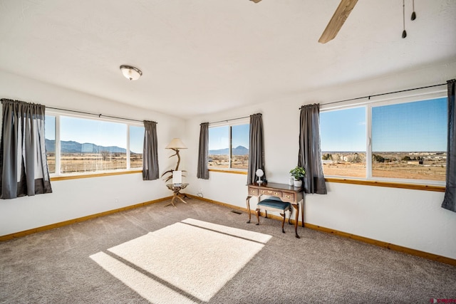 carpeted spare room with ceiling fan, a healthy amount of sunlight, and a mountain view