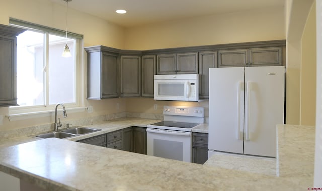 kitchen with pendant lighting, white appliances, dark brown cabinetry, sink, and plenty of natural light